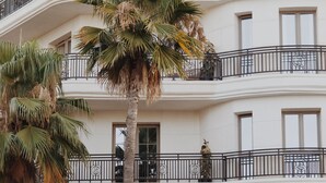 Un edificio de varios pisos con balcones, palmeras y ventanas.