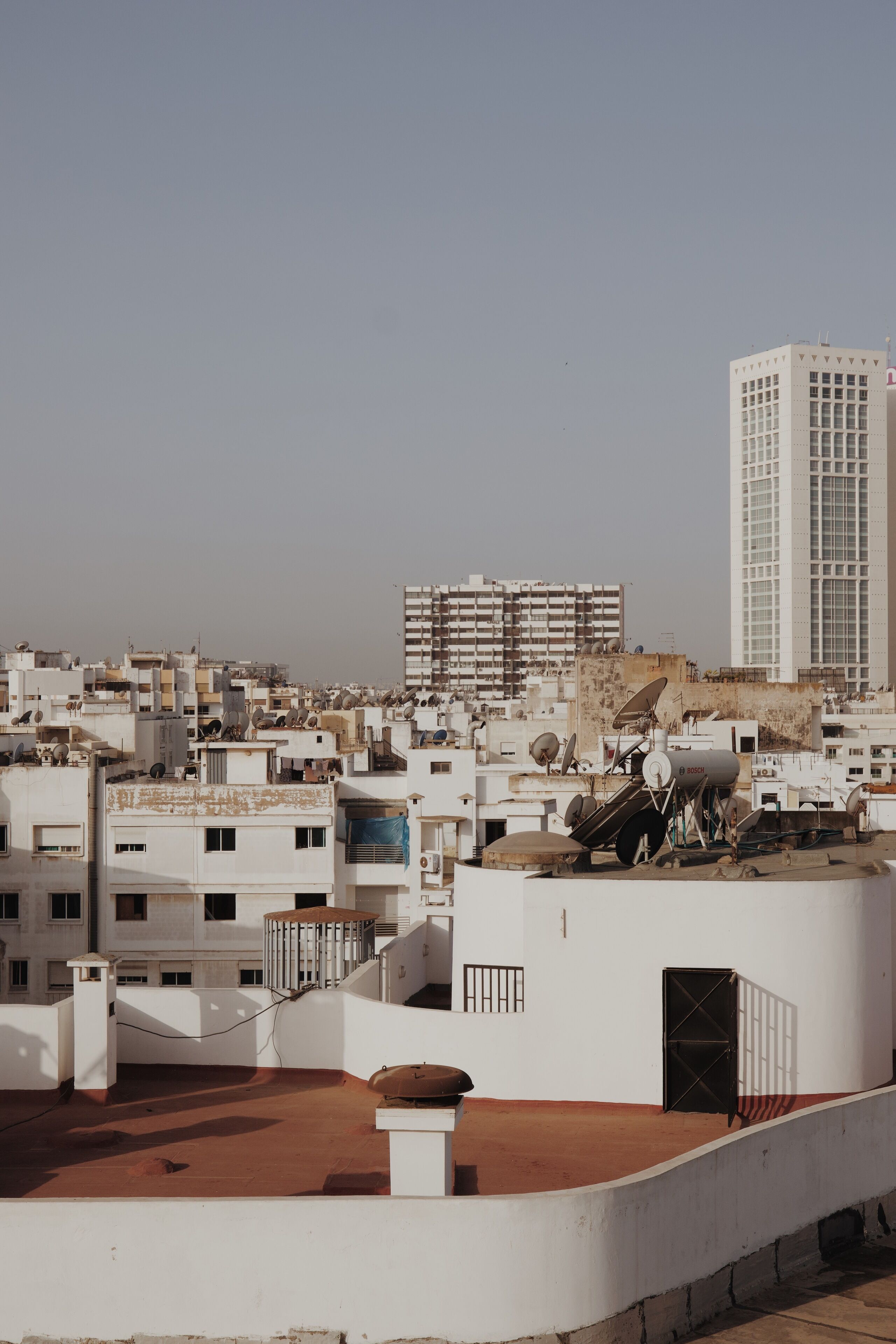 A rooftop with satellite dishes, a water tank, and a small structure.