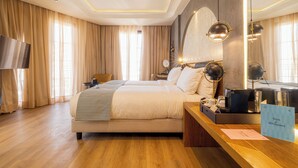 Habitación de hotel con una cama grande, un escritorio con computadora y teléfono, una televisión y un cartel que indica los servicios de la habitación.
