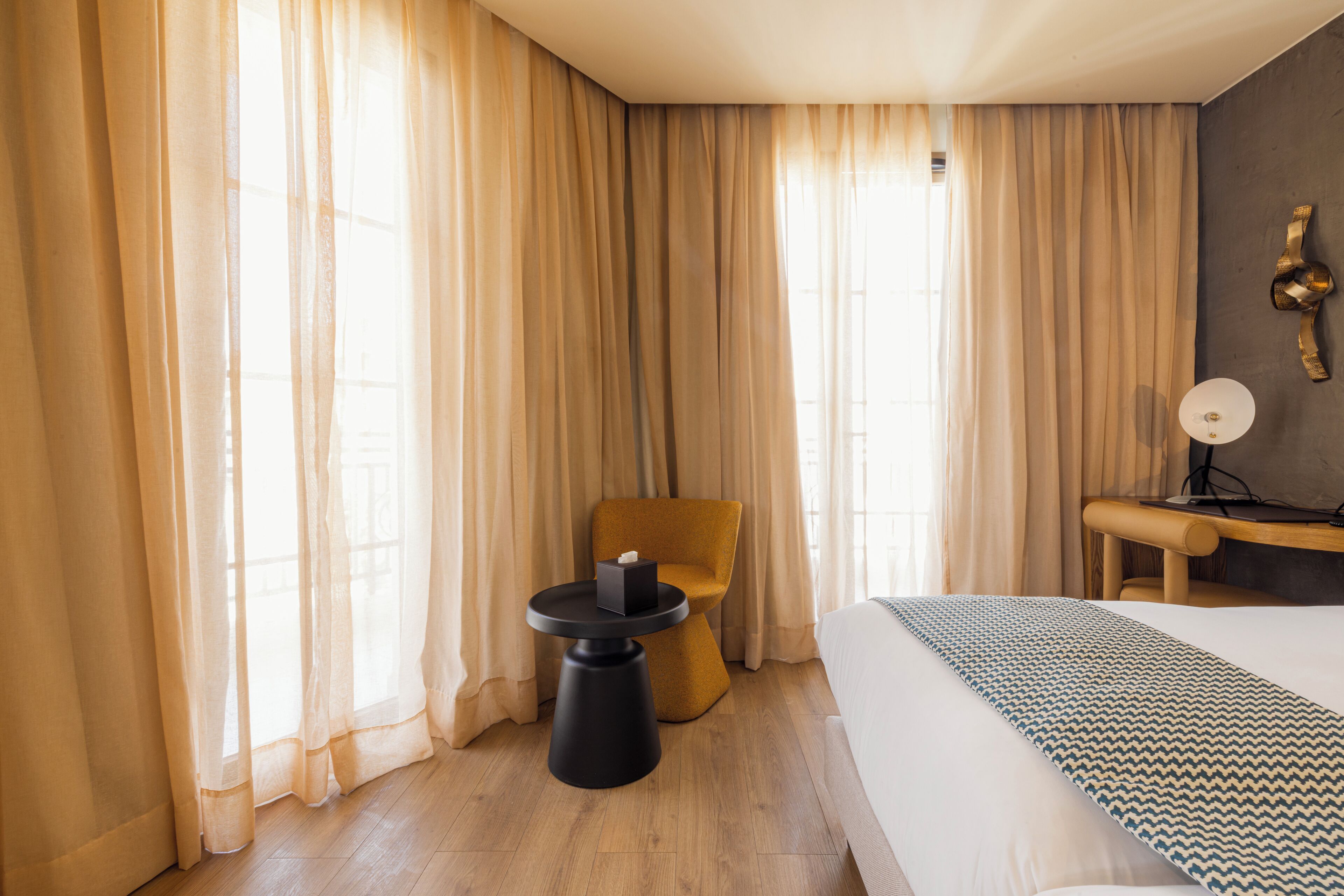 Ein Hotelzimmer mit Bett, kleinem Tisch, Stuhl und Schreibtisch mit Lampe.