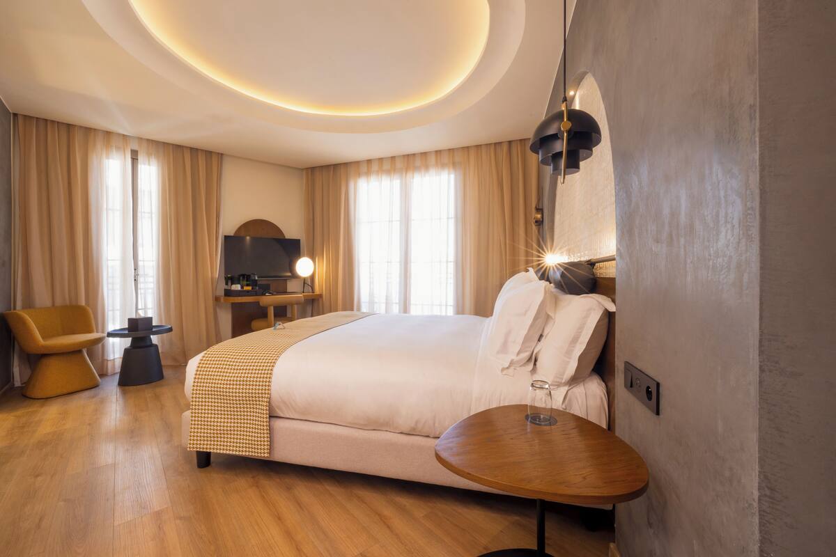 Une chambre d’hôtel moderne équipée d’un grand lit, d’un bureau, d’une chaise et d’une table ronde.