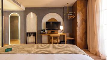A modern hotel room with a large bed, a desk with a TV, and a mirror.