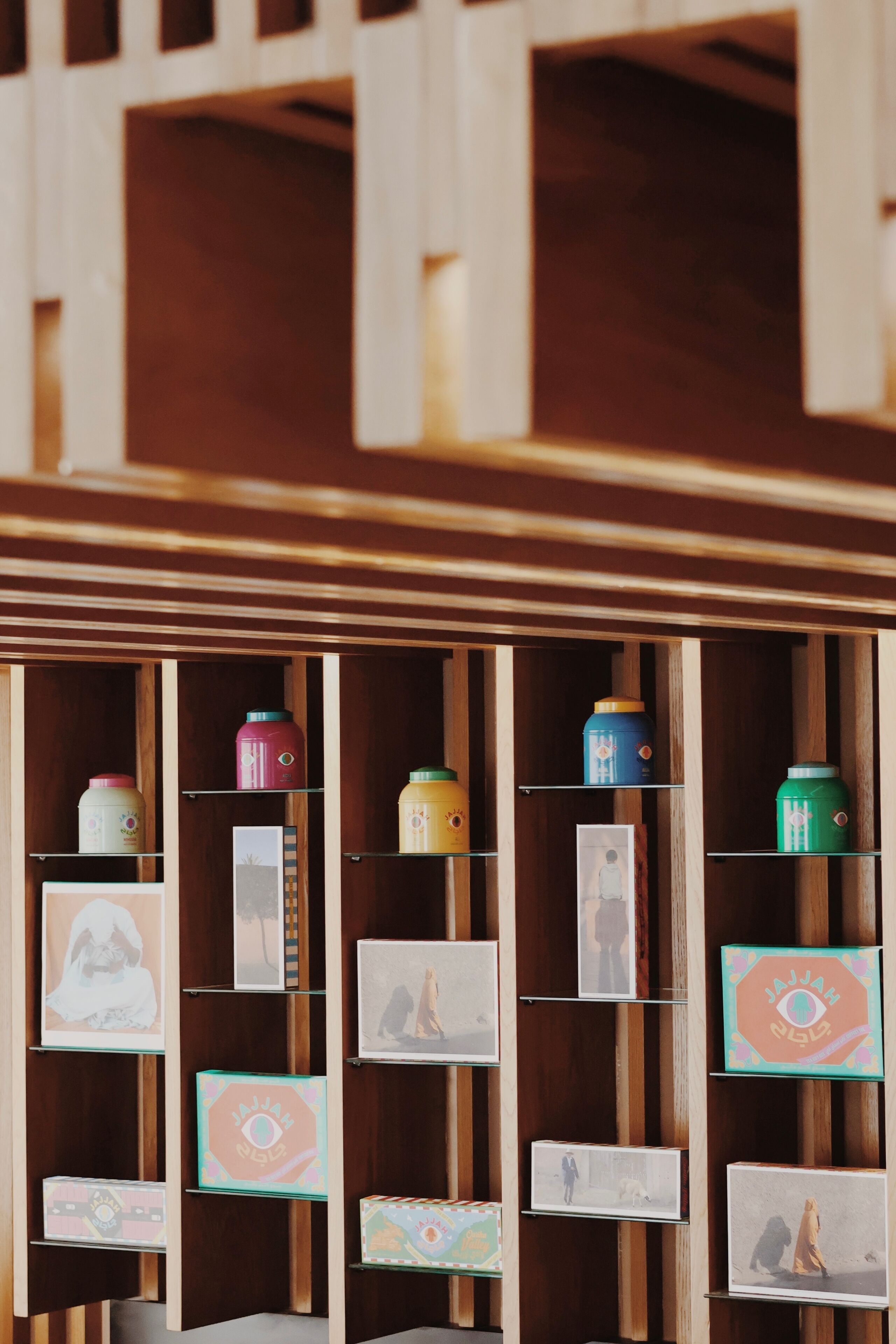 Una estantería de madera con diversos objetos, entre ellos recipientes de colores y cuadros enmarcados.