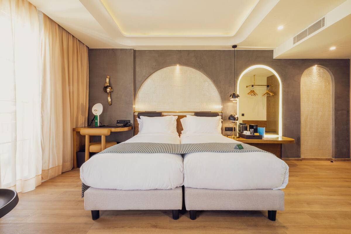 Un lit double avec une tête de lit, des tables de chevet, un miroir et une petite table de nuit.