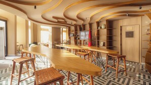 Un interior moderno con una barra de madera larga, varias zonas de estar y un suelo con diseño.