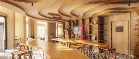 Un intérieur moderne avec un long bar en bois, plusieurs espaces salon et un sol à motifs.