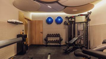 A gym with exercise equipment, a treadmill, and a wall-mounted dumbbell rack.