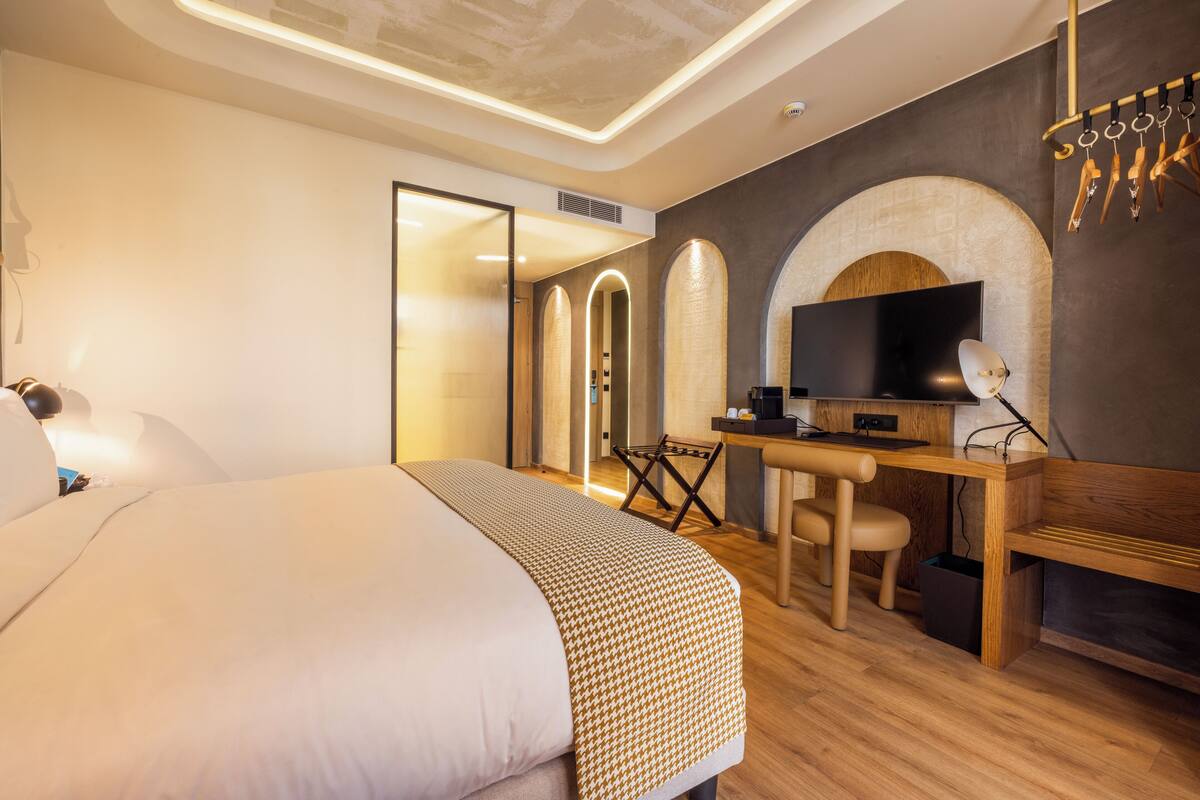 Une chambre d’hôtel moderne avec un grand lit, un bureau équipé d’un ordinateur, une télévision et une cheminée.