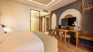Una habitación de hotel moderna con una cama grande, un escritorio con ordenador, un televisor y una chimenea.