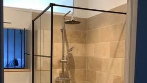 Een douchecabine van glas met een handdouche en een wandmengkraan.