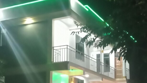 A two-story building with a balcony, potted plants, and a staircase.