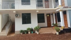A two-story building with a balcony, a staircase, and potted plants.