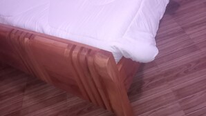 A bed with a wooden headboard, white bedding, and a wooden floor.