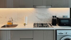 Ett modernt kök med en inbyggd gasspis, en mikrovågsugn, en brödrost och en tvättmaskin.