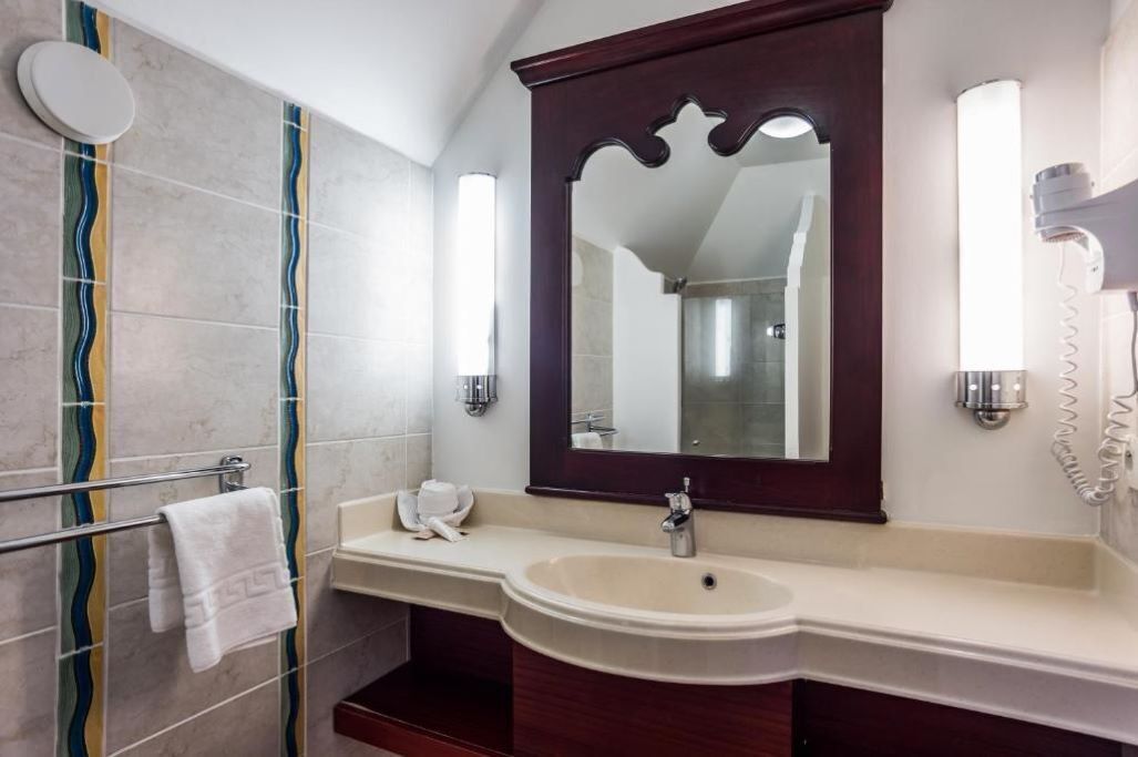 Une salle de bain équipée d’un meuble-lavabo, d’un miroir, d’un porte-serviettes et d’un sèche-cheveux.
