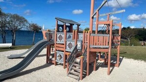 A playground with a slide and climbing structures, located on a sandy area with a view of the sea in the background. - Studio Avec Piscine et Plages Accessibles à Pieds (Sainte-Luce)