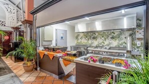 A buffet area with various food stations, a kitchen in the background, and decorative plants. - Studio Avec Piscine et Plages Accessibles à Pieds (Sainte-Luce)