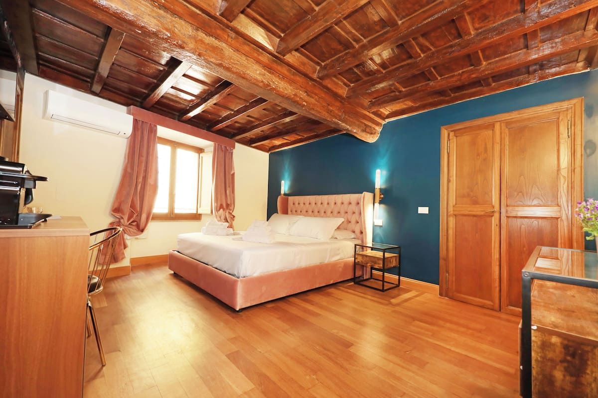 A bedroom with a wooden ceiling, a bed, a desk, and a wardrobe.