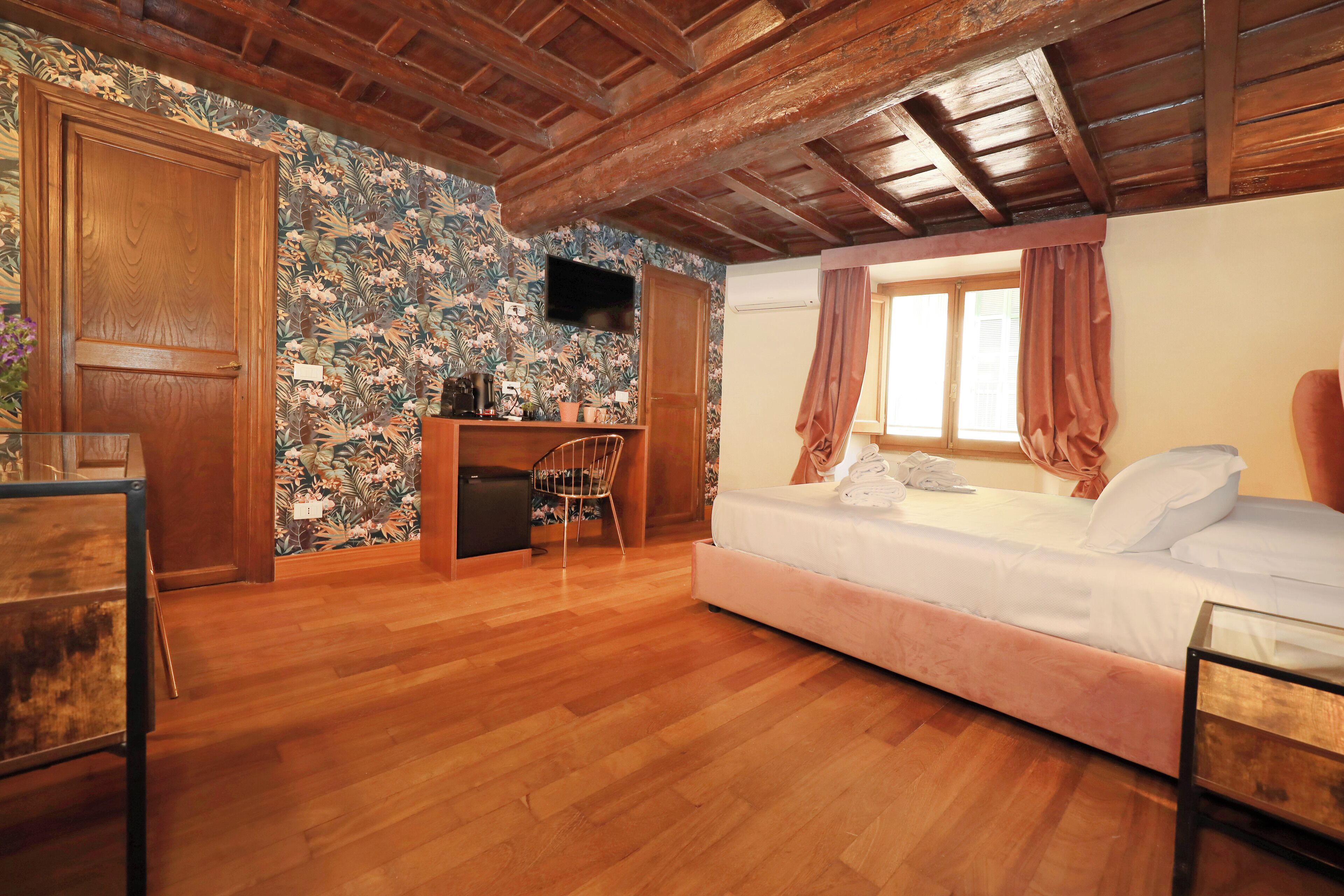 Ein Schlafzimmer mit Holzbalkendecke, einem Bett, einem Schreibtisch und einem Stuhl.