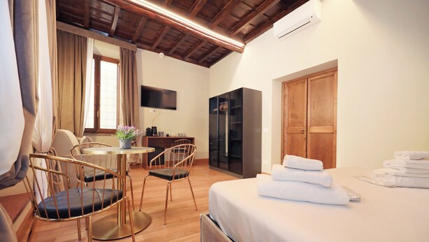 A hotel room with a bed, a desk, a chair, a wardrobe, and a television. - Golden Pantheon Rooms (Rome)