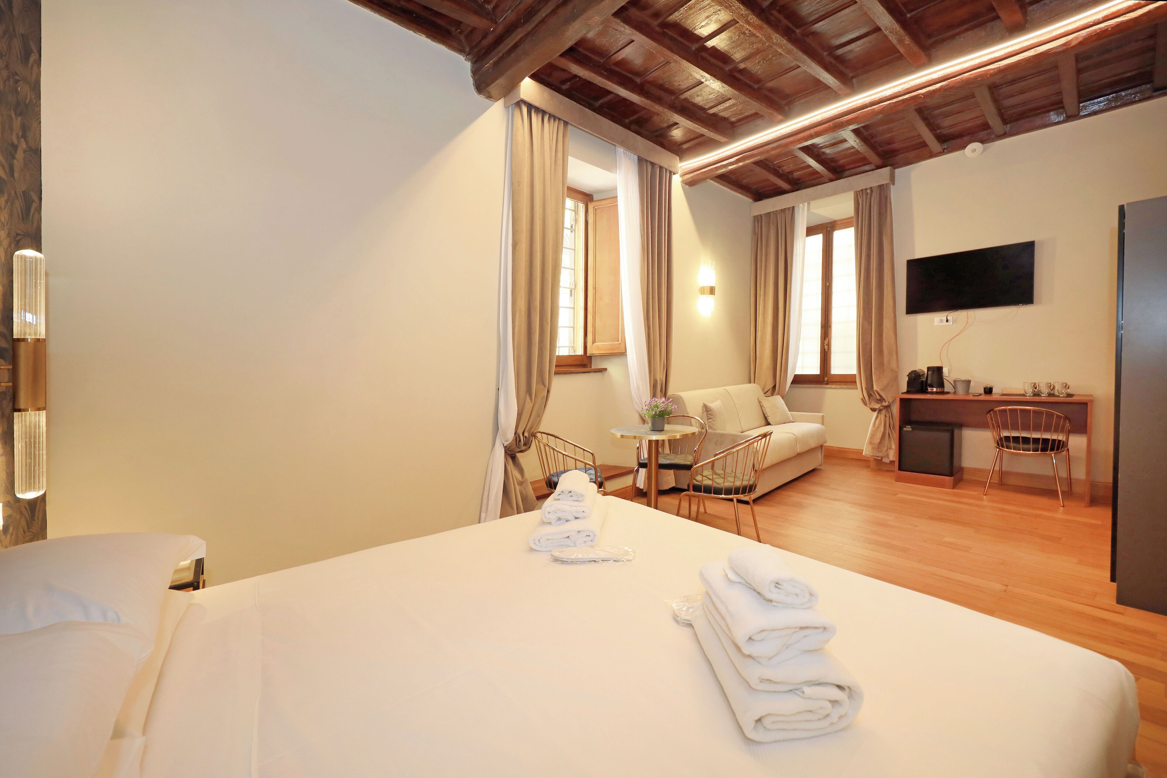 Une chambre d’hôtel équipée d’un lit, d’un bureau, d’une chaise, d’une télévision et d’une petite table avec une lampe.