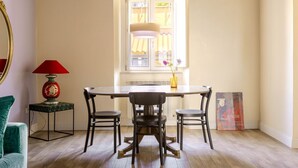 Ein Essbereich mit Tisch und Stühlen, einer Lampe, einer Vase mit Blumen und einem Poster an der Wand.