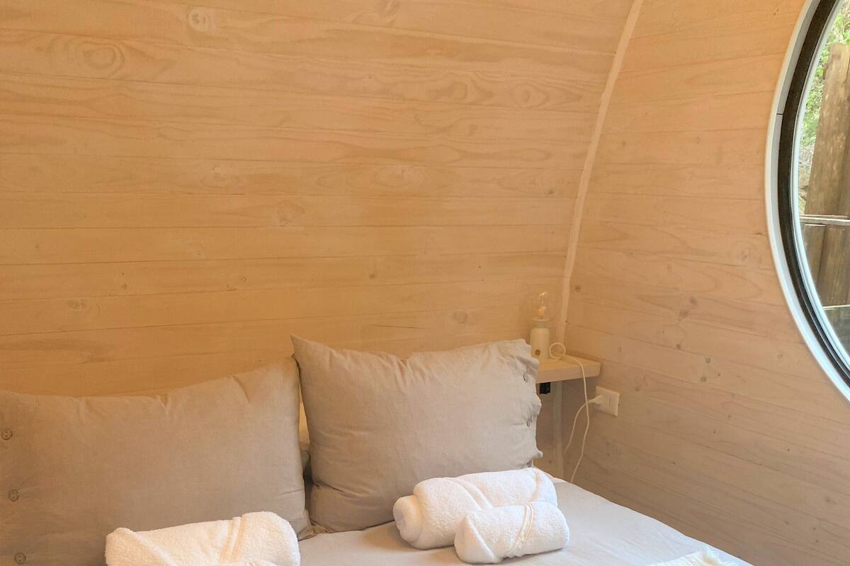 Una habitación acogedora con una cama, dos almohadas y dos toallas enrolladas.