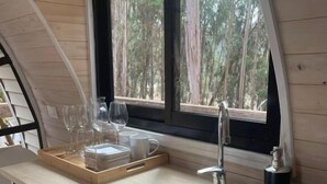 A kitchen with a wooden countertop, a sink, and a window overlooking a forest. - Parque Laguna de Zapallar (Zapallar)
