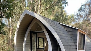 A small, modern cabin with a curved roof and a wooden deck. - Parque Laguna de Zapallar (Zapallar)