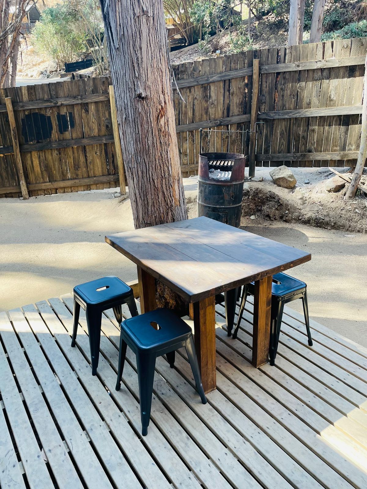 Una terraza de madera con una mesa y cuatro sillas.