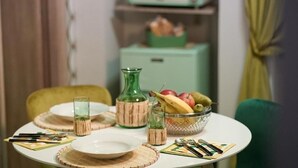 A dining table set with plates, cutlery, and a bowl of fruit. - Posillipo Apartment (Napoli)