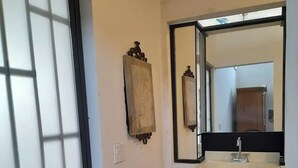 A bathroom with a tiled floor, a sink with a mirror above it, and a door with a frosted glass panel. - Central Location -"FRIDA" (Cabo San Lucas)