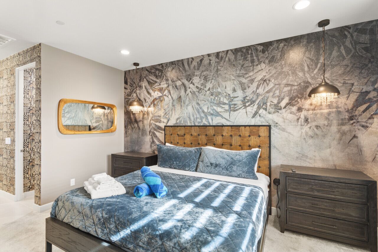 Un dormitorio con una cama grande, dos mesitas de noche, un espejo y una pared con textura.
