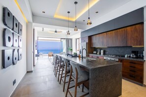 Cocina moderna con una isla grande, taburetes de bar y vistas al exterior.