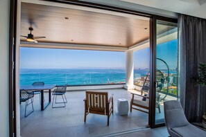 Un balcón con vista al mar, una mesa con sillas y un sofá.