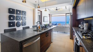 Une cuisine moderne dotée d’un îlot central, d’appareils électroménagers intégrés et offrant une vue sur l’extérieur.