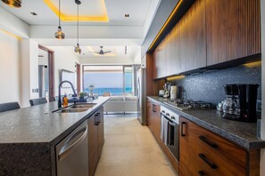A modern kitchen with a central island, stainless steel appliances, and a view to the outside.