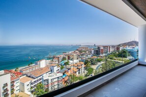 A balcony with a view of a coastal cityscape, including buildings and the sea.