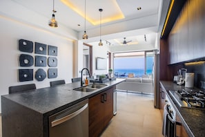 Una cocina moderna con una isla central, electrodomésticos integrados y vistas al mar.