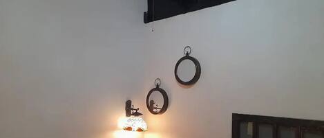 A room with a white wall, a table with a lamp, and three circular wall decorations.