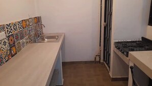 Een kleine keuken met een spoelbak, een fornuis en een betegelde achterwand.