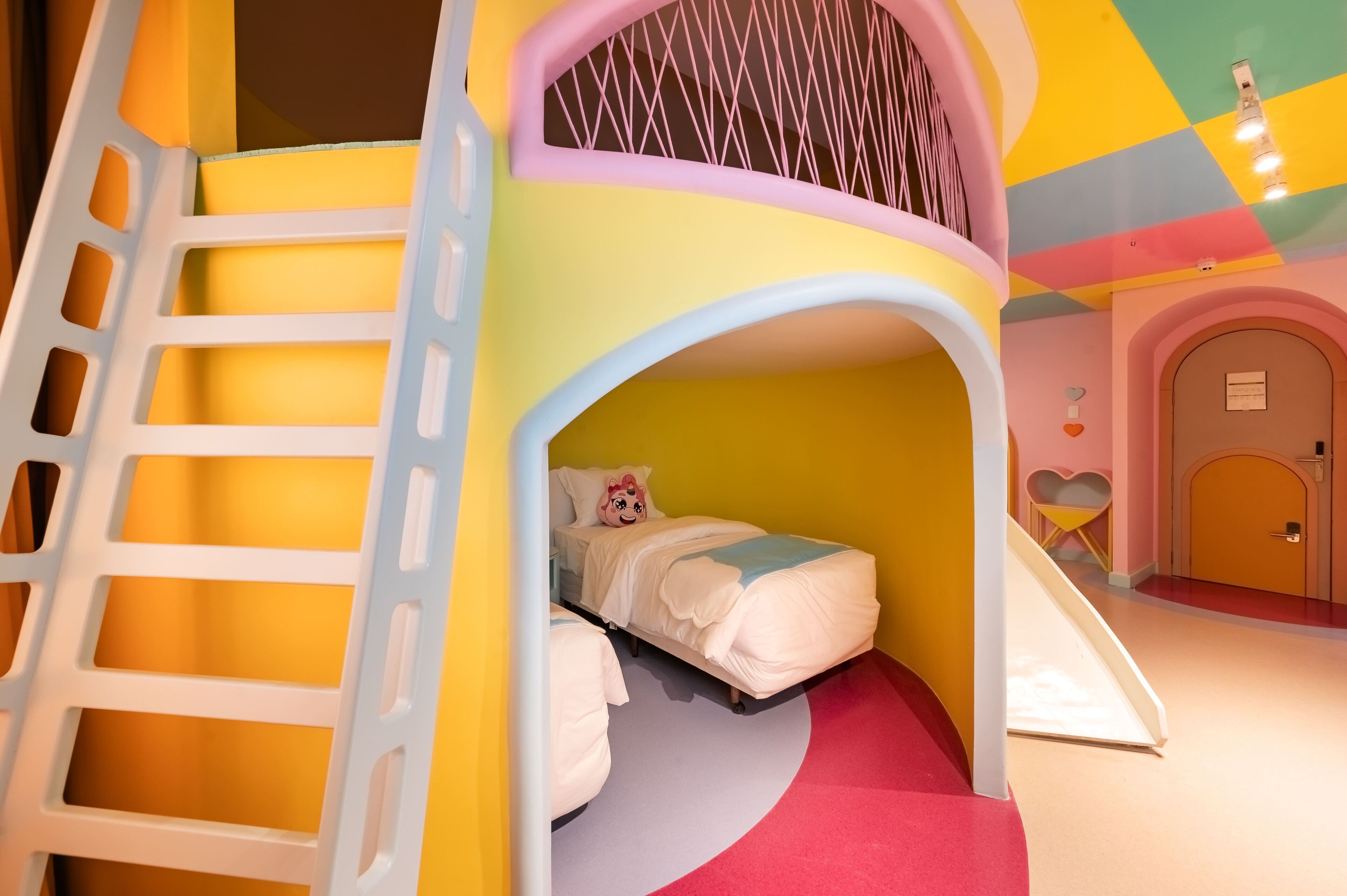 Una casita de juegos para niños con un tobogán, una cama y una silla con forma de corazón.