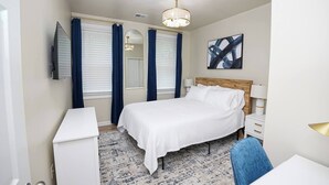 Een hotelkamer met een bed, een bureau, een stoel, een televisie en een schilderij aan de muur.