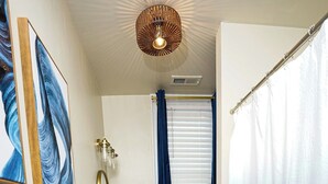 Een badkamer met een houten vloer, een witte wastafel en een blauw douchegordijn.