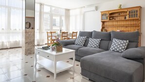 A modern living room with a grey sofa, a white coffee table, and a wooden cabinet with shelves. - Charming flat for 6 people in Felanitx, Mallorca (Felanitx)