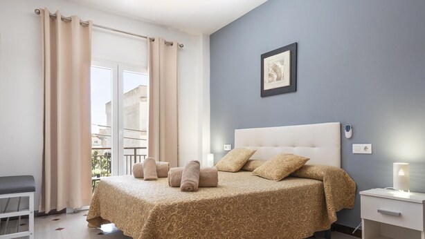 A bedroom with a bed, bedside table, and a view of the outside. - Charming flat for 6 people in Felanitx, Mallorca (Felanitx)