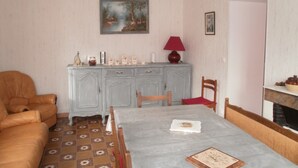 Comedor con mesa, sillas, sofá, aparador y un cuadro en la pared.