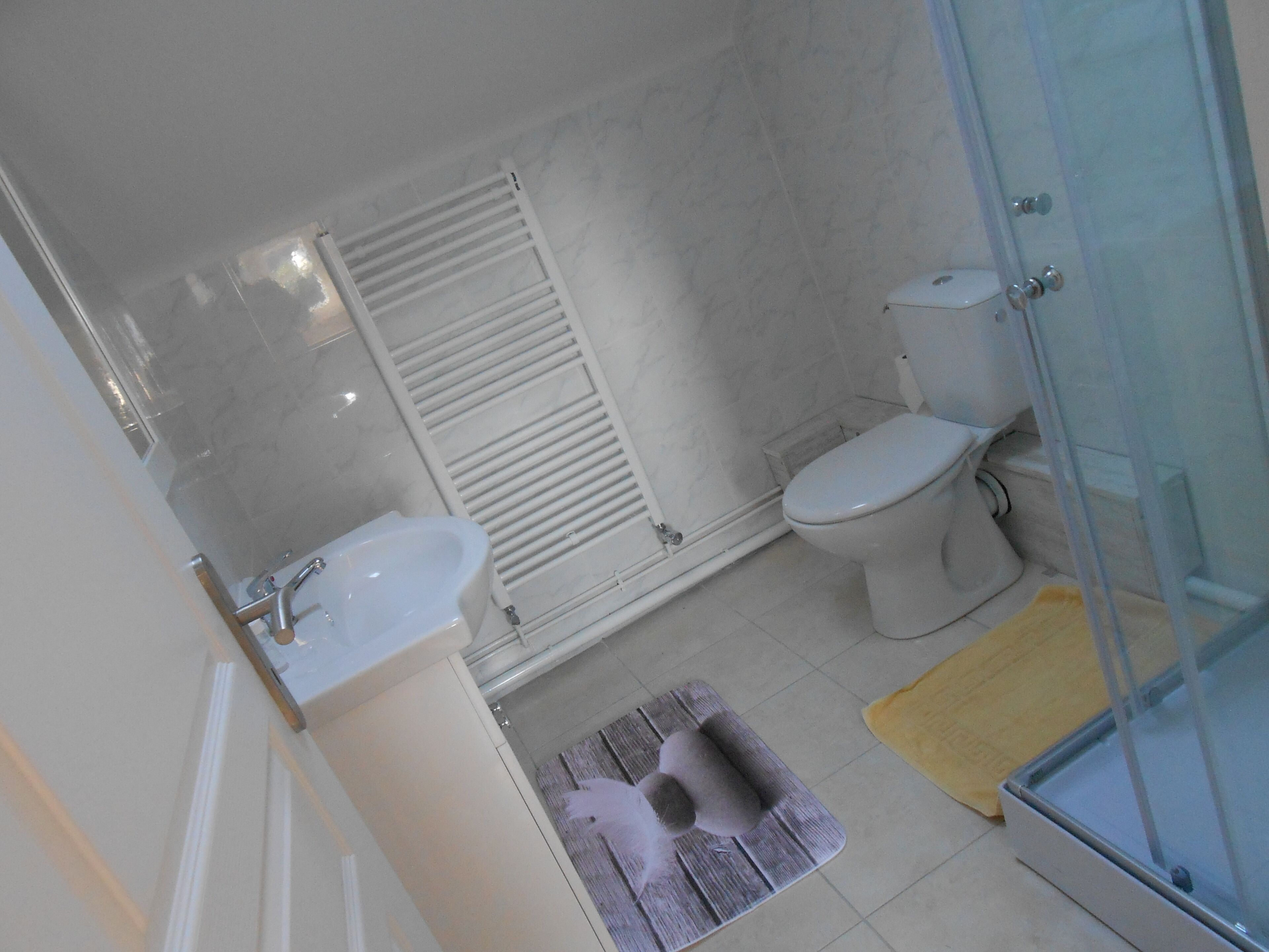 Et badeværelse med toilet, bidet, vask og bruseområde.