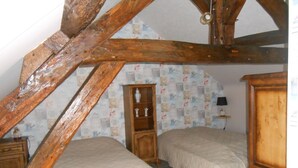 Un dormitorio con dos camas, vigas de madera, un tocador y una mesita de noche.