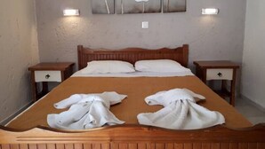 Ein ordentlich bezogenes Bett mit Handtüchern, einem hölzernen Kopfteil und einem an der Wand hängenden Blumenbild.